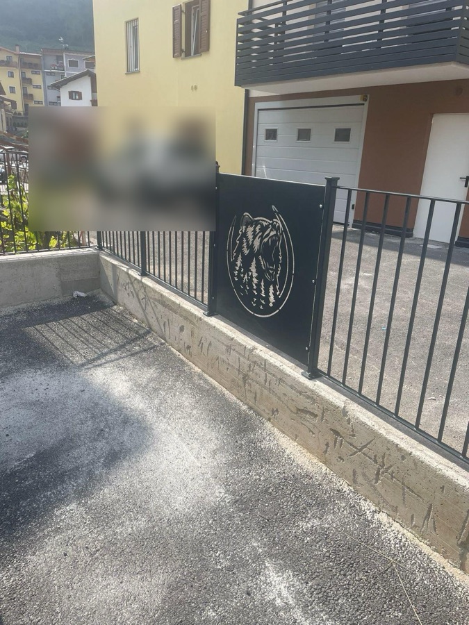 Recinzione in ferro con un pannello decorato a taglio laser con la figura di un orso, a Cavedago.